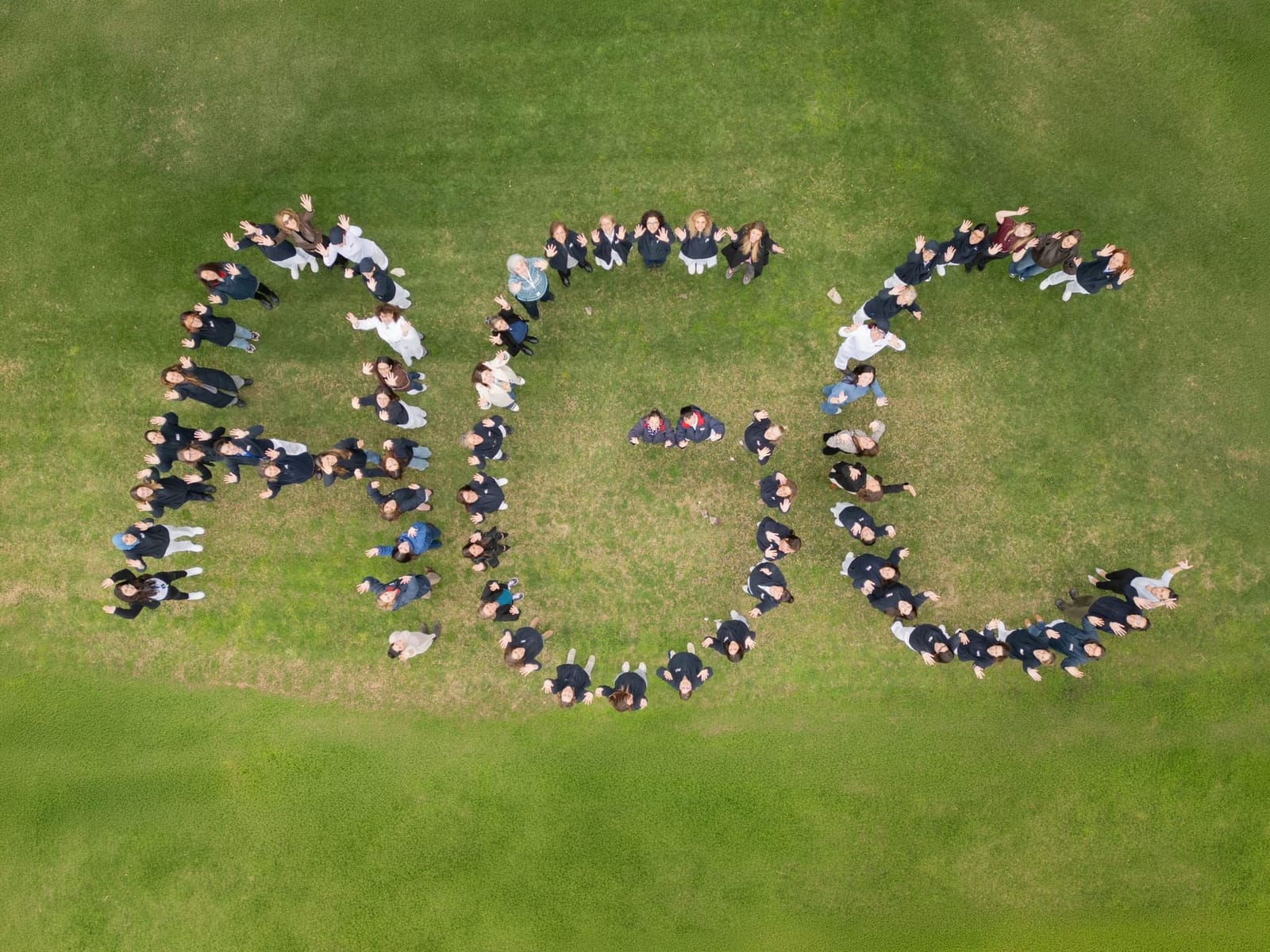 AGC Group colleagues standing together to form the letters A G C, photographed from above